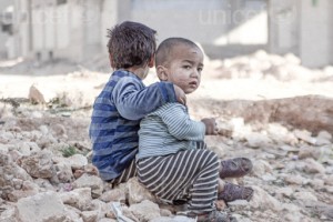 On 25 December 2015 in Aleppo in the Syrian Arab Republic, Esraa, 4, and her brother Waleed, 3, sit on the ground near a shelter for internally displaced persons.