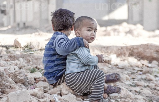On 25 December 2015 in Aleppo in the Syrian Arab Republic, Esraa, 4, and her brother Waleed, 3, sit on the ground near a shelter for internally displaced persons.